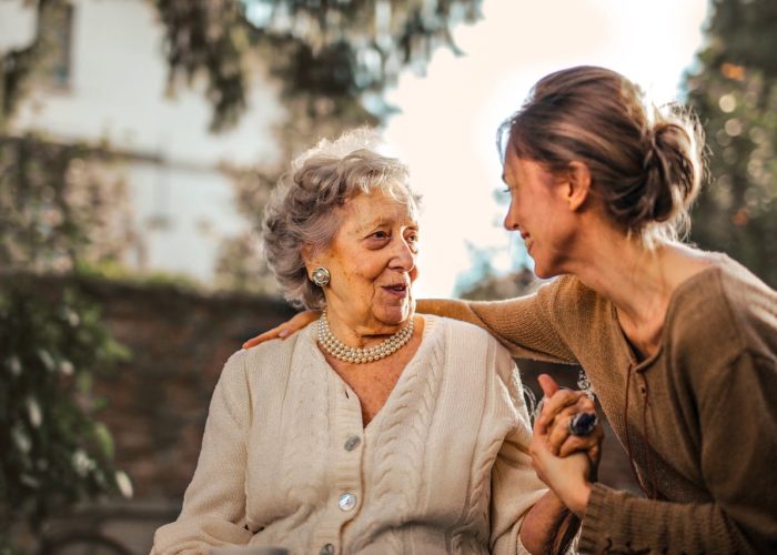 Joyful adult daughter greeting happy surprised senior mother in garden